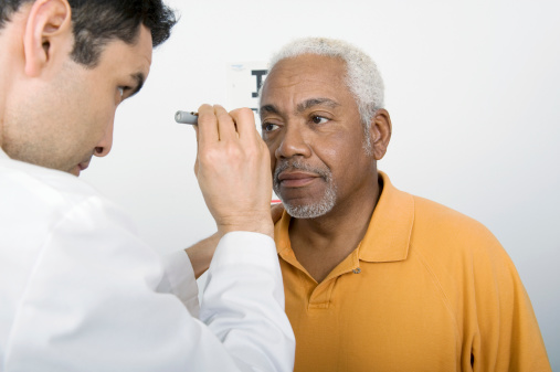 Photograph of a doctor performing an eye examination on an elderly patient